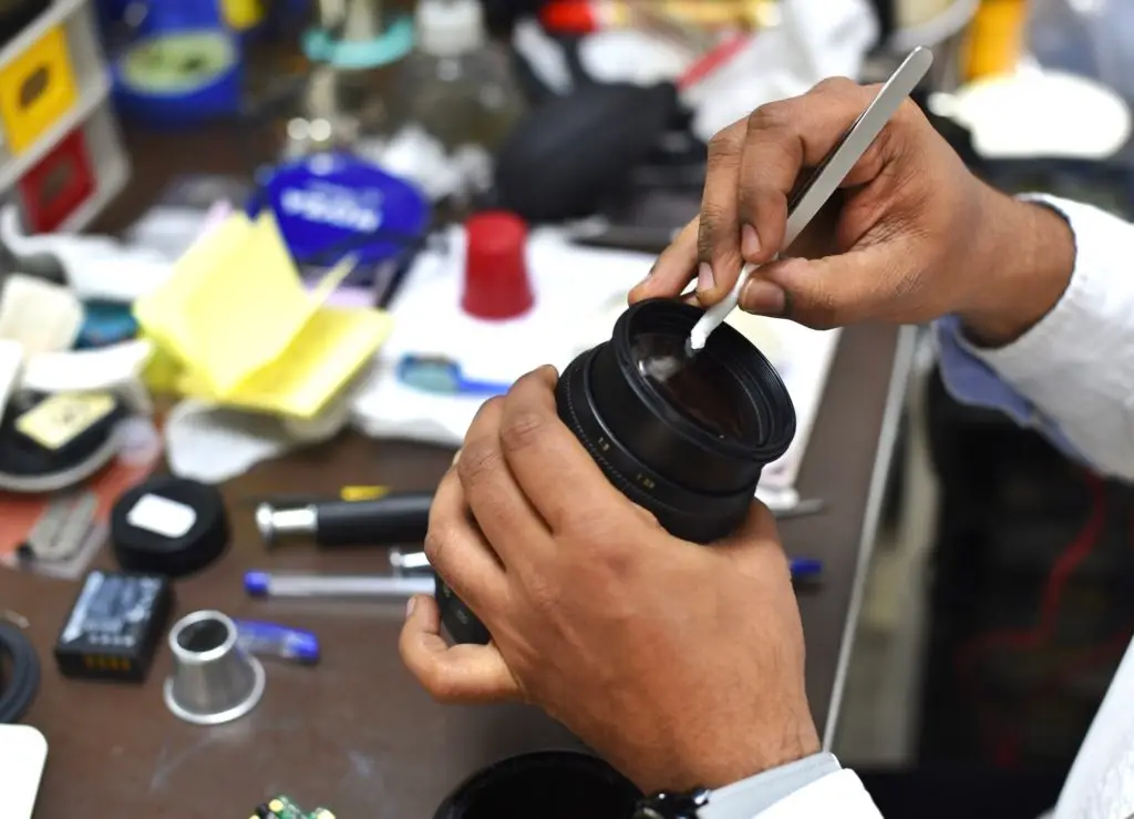 Highly trained camera technician puts finishing touches on a lens after cleaning the camera